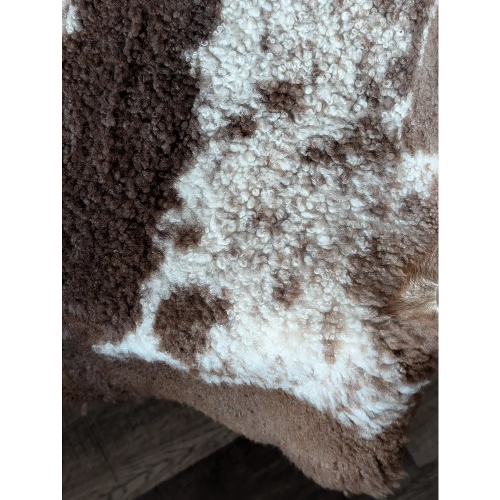 A cozy brown and white tibet highland spotted sheepskin blanket with plush textured surface perfect for warmth
