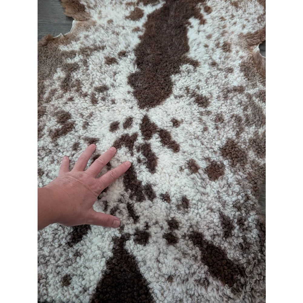 A plush brown and white tibet highland spotted sheepskin rug with a soft curly texture perfect for cozy spaces