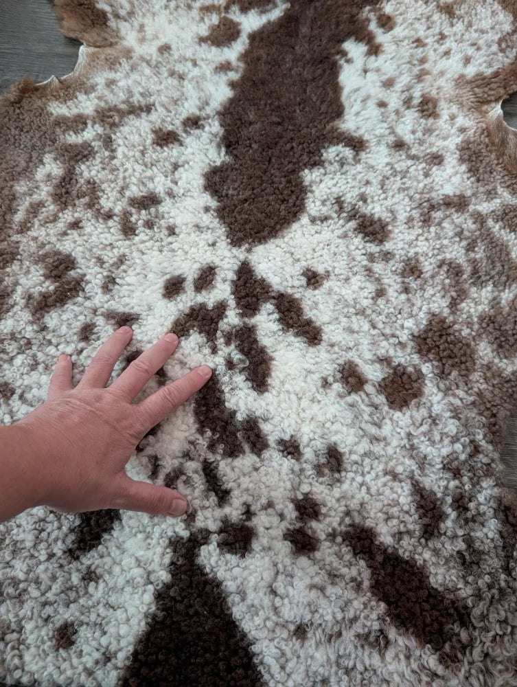 A plush brown and white tibet highland spotted sheepskin rug with a soft curly texture perfect for cozy spaces