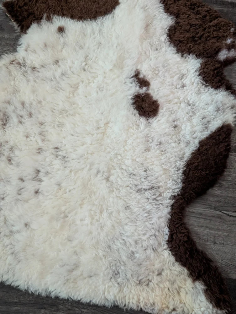 A plush cream and brown tibet highland spotted sheepskin rug with a soft curly texture perfect for cozy spaces