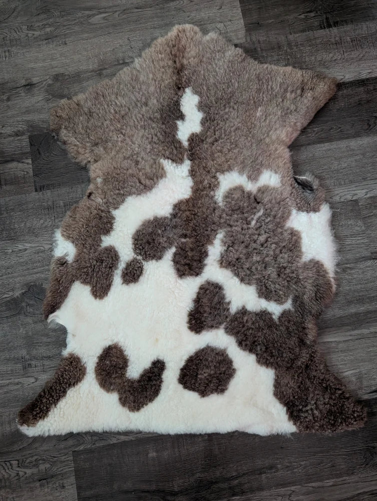 Brown and white tibet highland spotted sheepskin rug with fluffy natural texture measuring 40 by 25 inches
