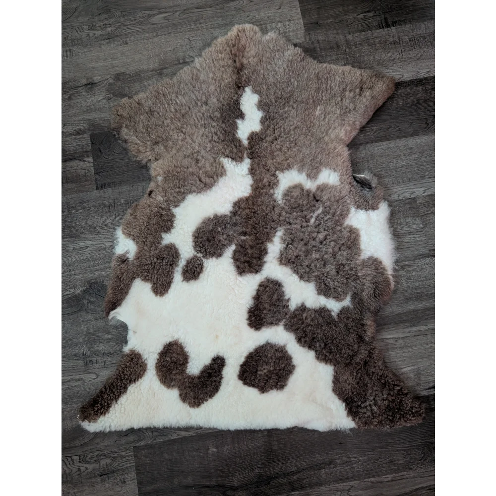 Brown and white tibet highland spotted sheepskin rug with fluffy natural texture measuring 40 by 25 inches