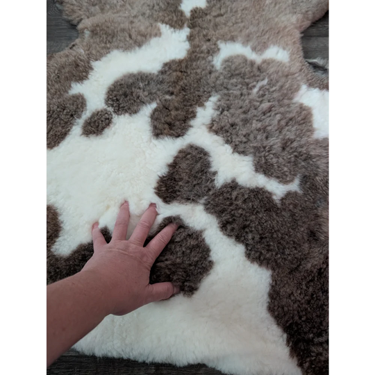 A plush 40 x 25 inch tibet highland spotted sheepskin rug with a brown and white spotted pattern grade a quality