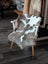A cozy tibet highland spotted sheepskin throw in natural brown and white draped over a minimalist wooden chair