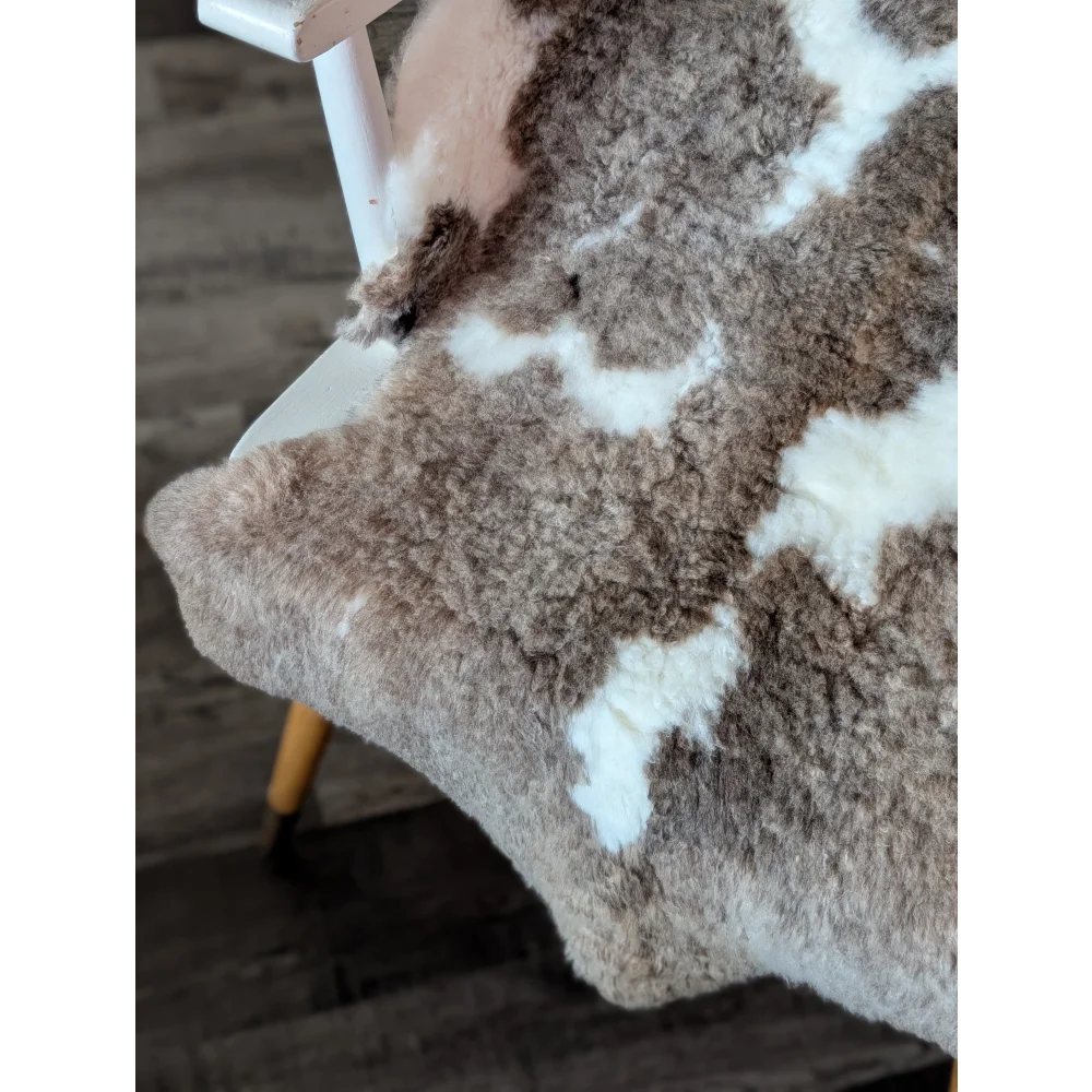 A cozy tibet highland spotted sheepskin rug with soft brown and creamy white patchwork fur in 40 by 25 inches