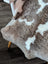 A cozy tibet highland spotted sheepskin rug with soft brown and creamy white patchwork fur in 40 by 25 inches