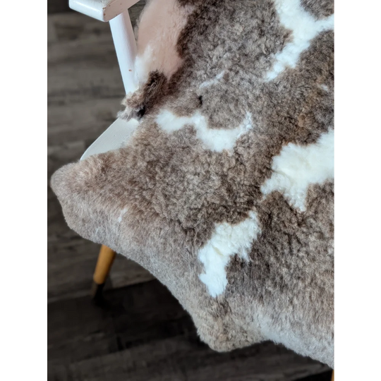 A cozy tibet highland spotted sheepskin rug with soft brown and creamy white patchwork fur in 40 by 25 inches