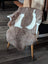 A soft natural brown and white tibet highland spotted sheepskin rug draped over the back of a wooden chair