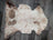 A soft cream and brown tibet highland spotted sheepskin rug with fluffy texture and organic shape 40 x 25 inches