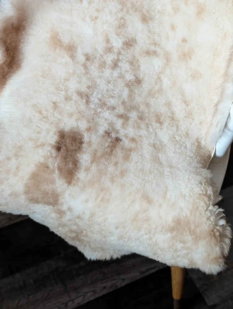 Cream-colored tibet highland spotted sheepskin blanket with soft fluffy texture and natural brown patches grade a quality