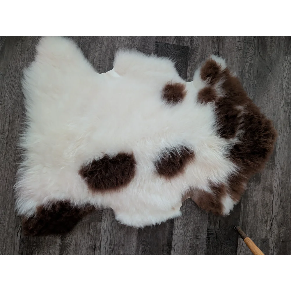 A plush white and brown spotted tibet highland spotted sheepskin rug with soft fluffy texture in size 43.5 x 28 inches
