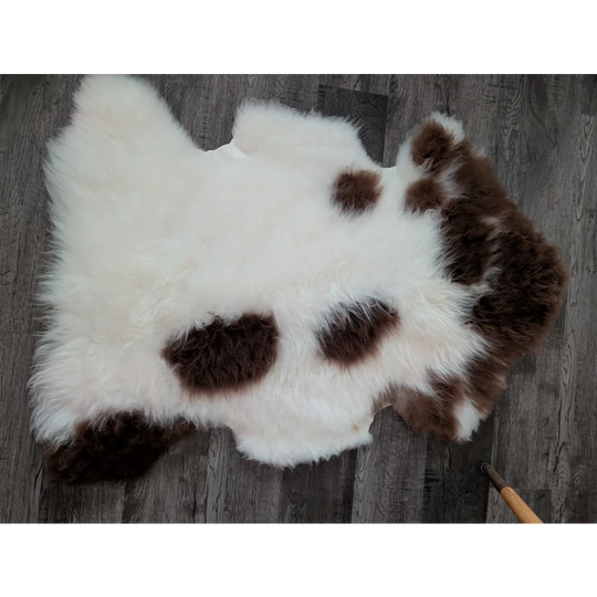 A plush white and brown spotted tibet highland spotted sheepskin rug with soft fluffy texture in size 43.5 x 28 inches