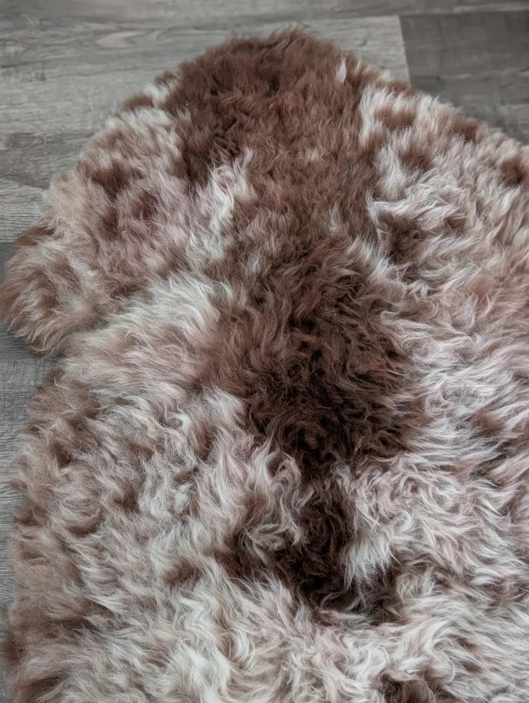 A plush tibet highland spotted sheepskin rug in brown and white with a soft natural texture measuring 47 by 25 inches