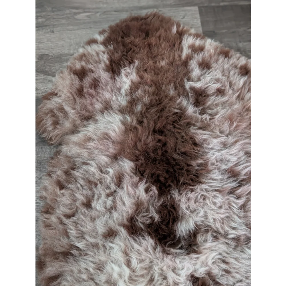 A plush tibet highland spotted sheepskin rug in brown and white with a soft natural texture measuring 47 by 25 inches