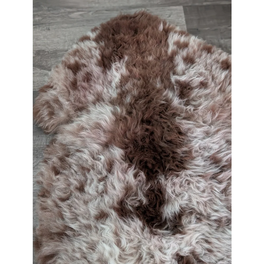 A plush tibet highland spotted sheepskin rug in brown and white with a soft natural texture measuring 47 by 25 inches