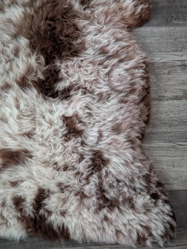 A plush cream and brown tibet highland spotted sheepskin rug 47 by 25 inches perfect for cozy decor