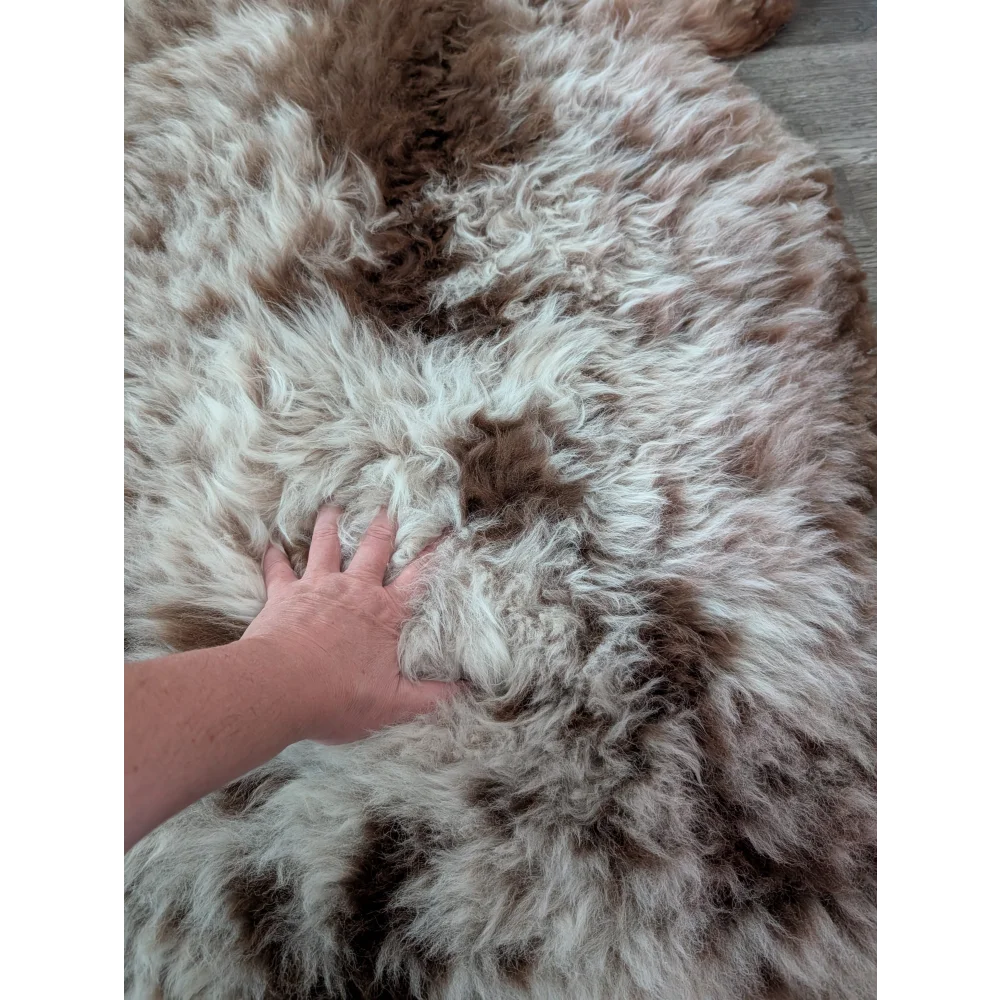 A plush tibet highland spotted sheepskin rug in cream and brown tones measuring 47 by 25 inches