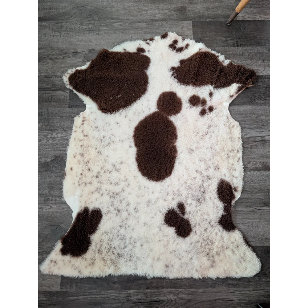 A plush cream and brown tibet highland spotted sheepskin rug with soft fluffy texture measuring 43.5 by 29.5 inches