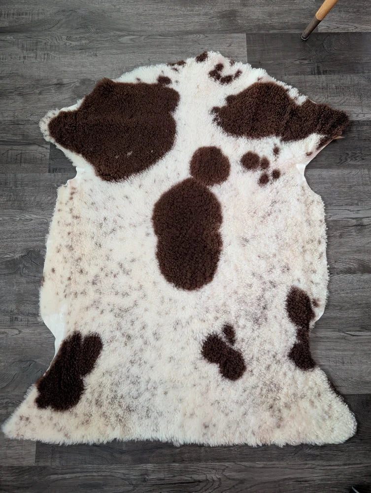 A plush cream and brown tibet highland spotted sheepskin rug with soft fluffy texture measuring 43.5 by 29.5 inches