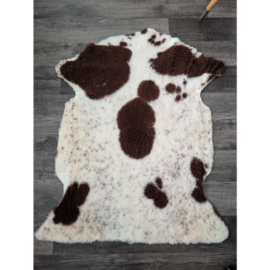 A plush cream and brown tibet highland spotted sheepskin rug with soft fluffy texture measuring 43.5 by 29.5 inches
