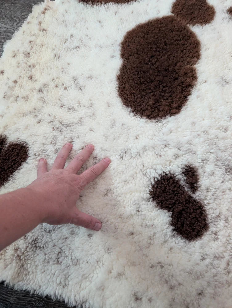 A plush white and brown tibet highland spotted sheepskin rug with a soft textured surface perfect for cozy spaces