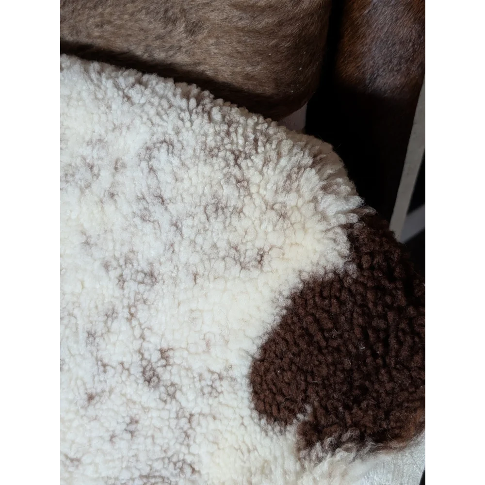 A cozy cream and brown tibet highland spotted sheepskin blanket with soft fluffy texture measuring 43.5 by 29.5 inches