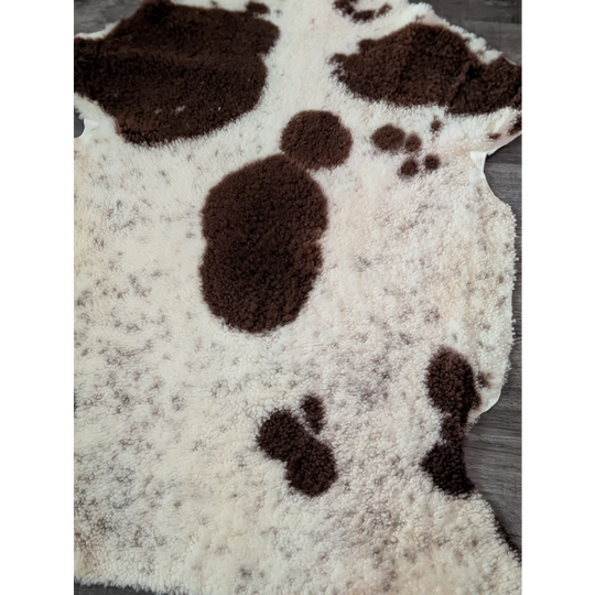 A plush cream-colored tibet highland spotted sheepskin rug with soft brown patches and fuzzy texture measuring 43.5 x 29.5 inches