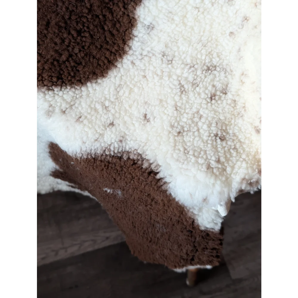 A plush cream and brown highland spotted sheepskin rug with soft fluffy texture 43.5 by 29.5 inches