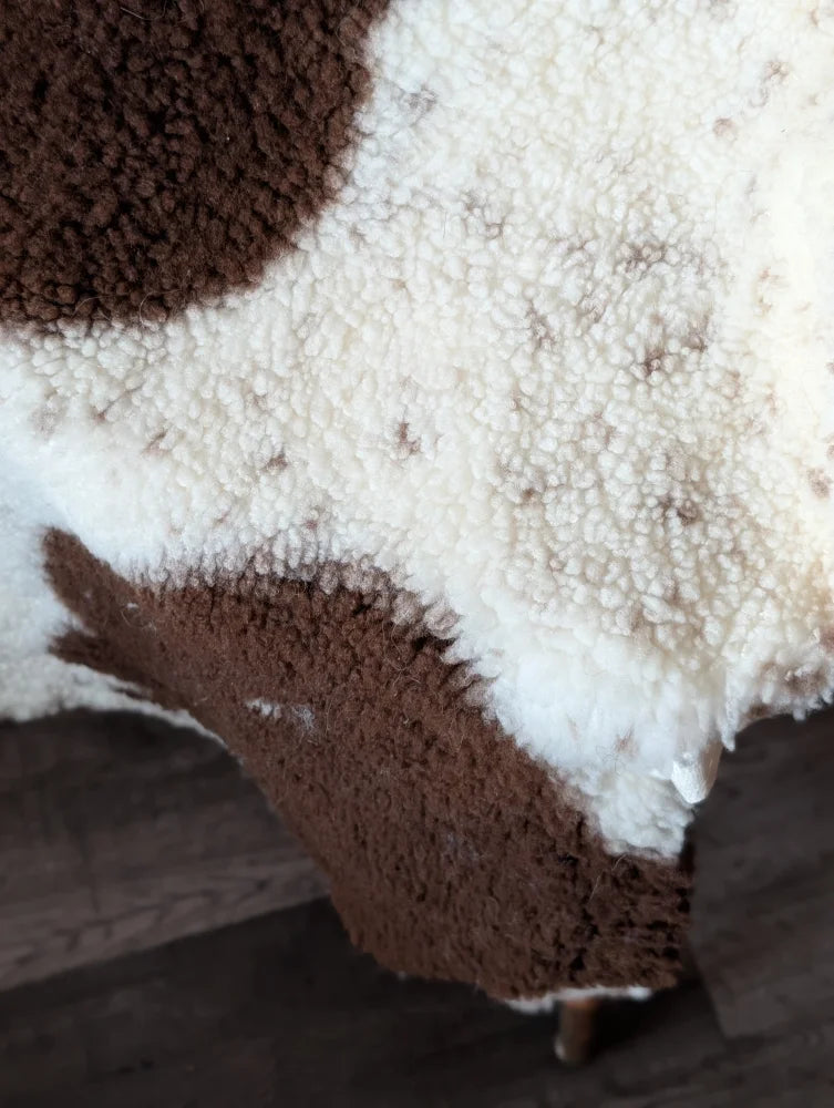 A plush cream and brown highland spotted sheepskin rug with soft fluffy texture 43.5 by 29.5 inches