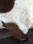 A plush cream and brown highland spotted sheepskin rug with soft fluffy texture 43.5 by 29.5 inches