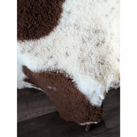 A plush cream and brown highland spotted sheepskin rug with soft fluffy texture 43.5 by 29.5 inches