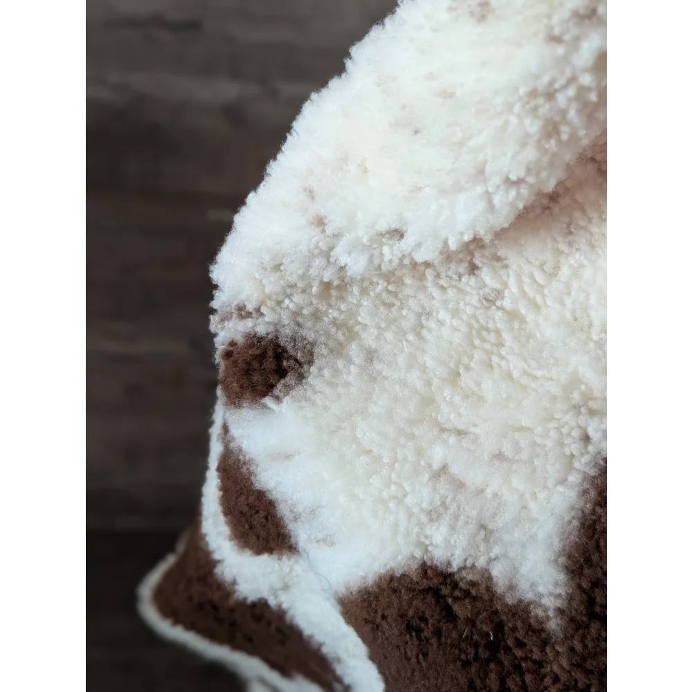 A cream and brown plush fleece blanket with a soft texture featuring a highland spotted sheepskin pattern