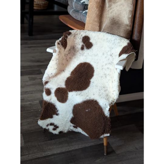 A plush white and brown highland spotted sheepskin blanket draped over a chair tibet highland spotted grade a