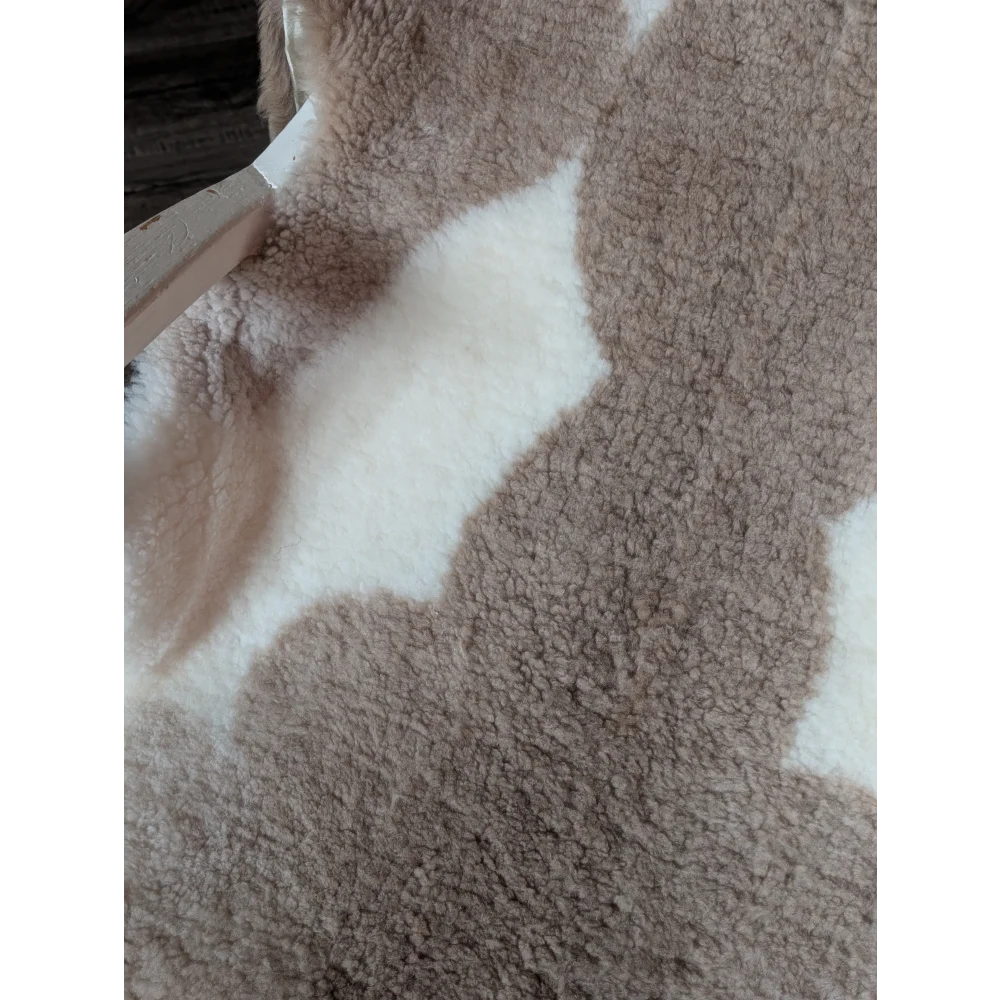 A cozy plush beige and white teddy bear style blanket made of grade a tibet highland spotted sheepskin measuring 41 x 25.5 inches