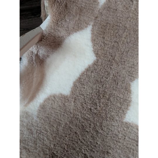 A cozy plush beige and white teddy bear style blanket made of grade a tibet highland spotted sheepskin measuring 41 x 25.5 inches