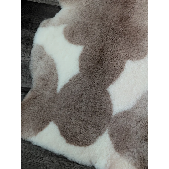 A plush tibet highland spotted sheepskin rug with creamy white and muted brown patches measuring 41 x 25.5 inches