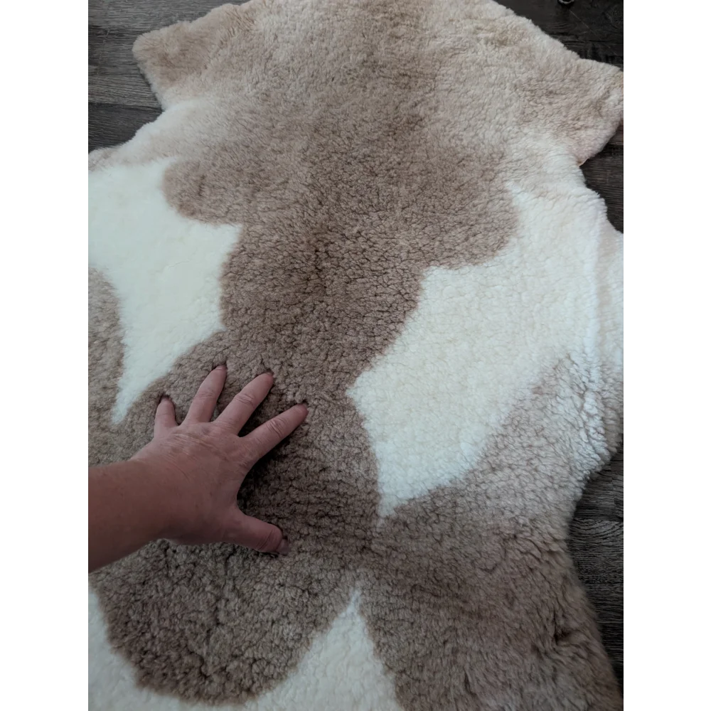 A soft tibet highland spotted sheepskin rug with creamy white and light brown fur patchwork in 41 x 25.5 size
