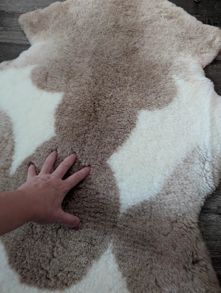 A soft tibet highland spotted sheepskin rug with creamy white and light brown fur patchwork in 41 x 25.5 size