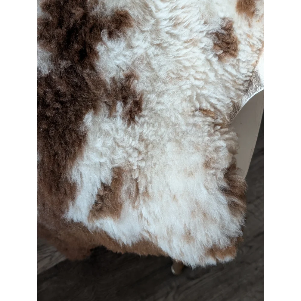 A plush tibet highland spotted sheepskin rug in natural white and brown measuring 42.5 by 26 inches