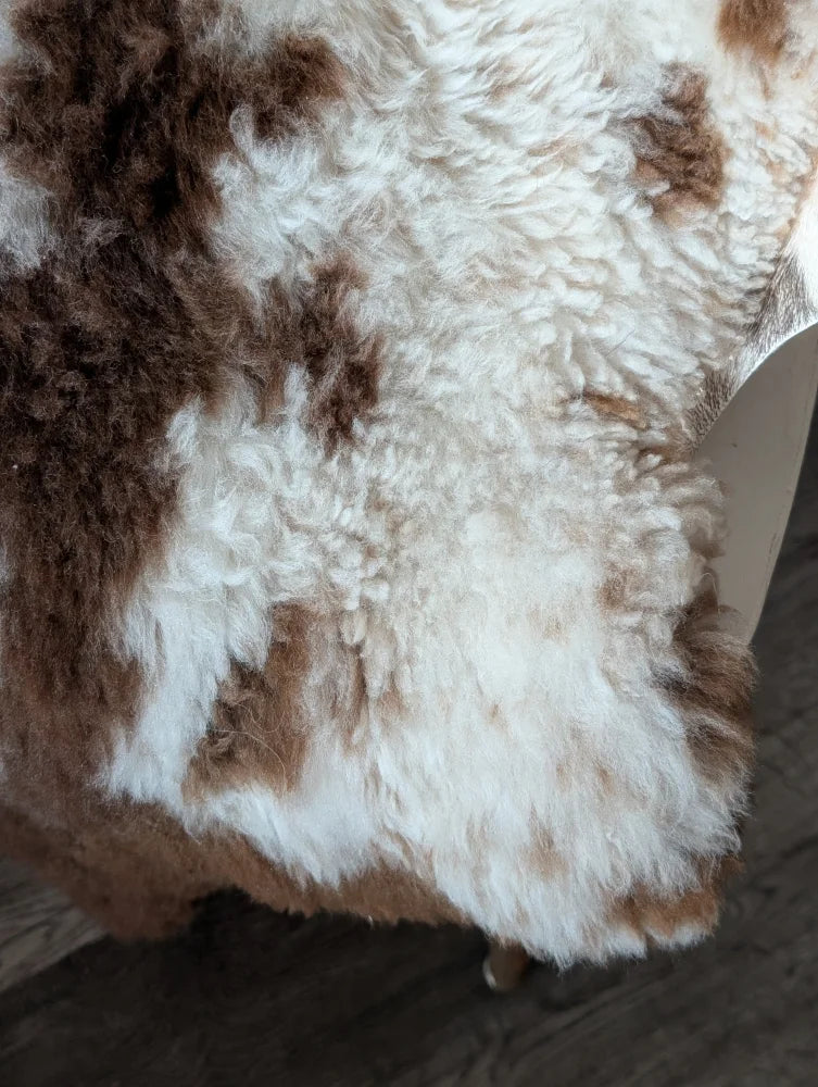 A plush tibet highland spotted sheepskin rug in natural white and brown measuring 42.5 by 26 inches