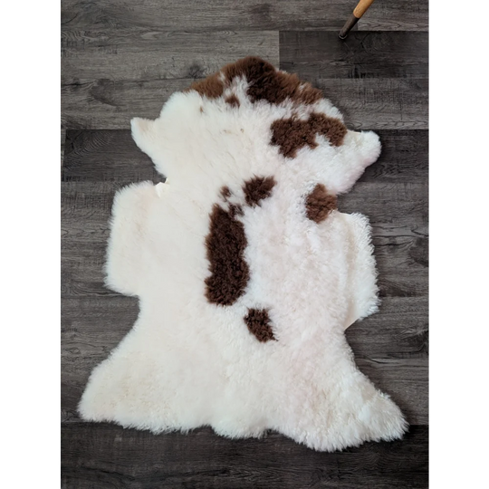 A plush white and brown highland spotted sheepskin rug with soft fluffy texture from tibet highland spotted grade a