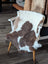 Brown and white highland spotted sheepskin throw draped over wooden chair made from tibet highland spotted wool