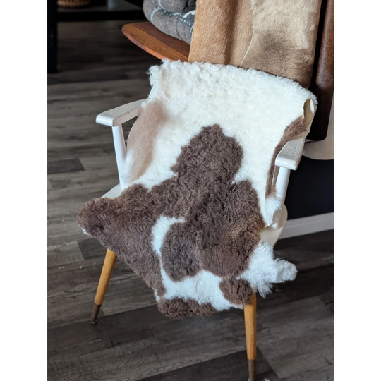 Brown and white highland spotted sheepskin throw draped over wooden chair made from tibet highland spotted wool