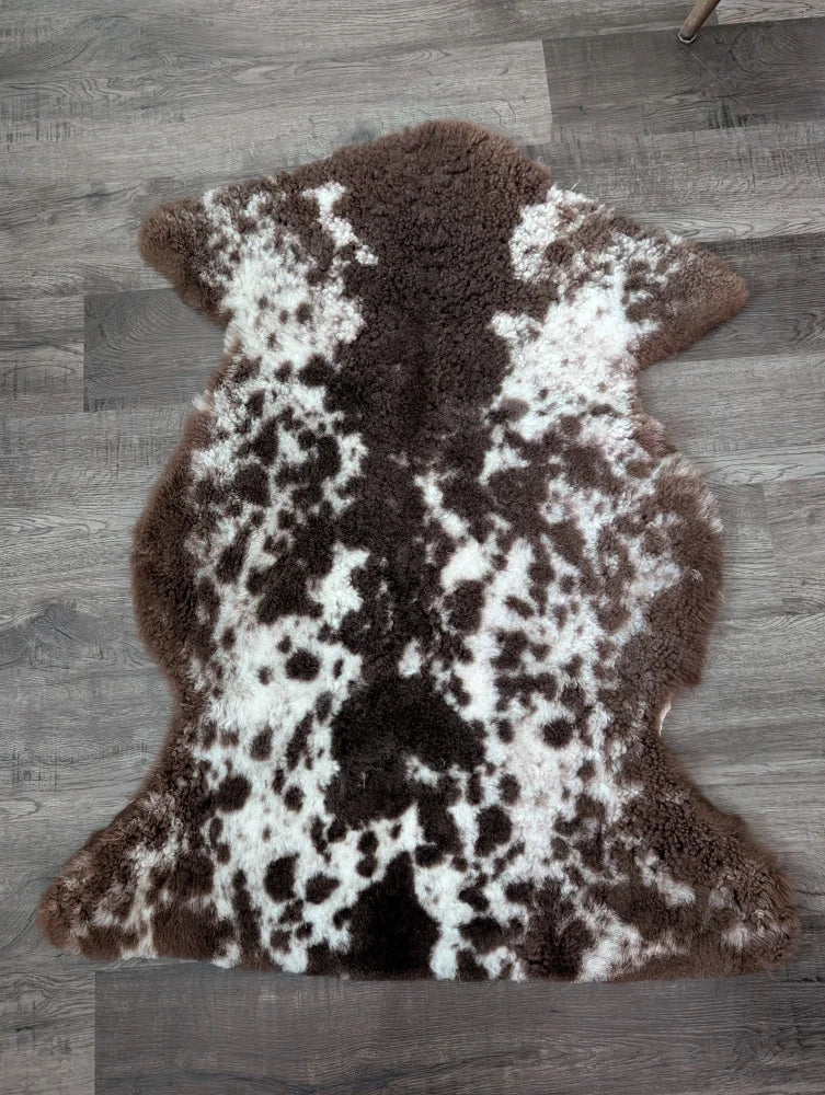 Brown and white tibet highland spotted sheepskin rug with plush natural fur texture sized 40 by 25 inches