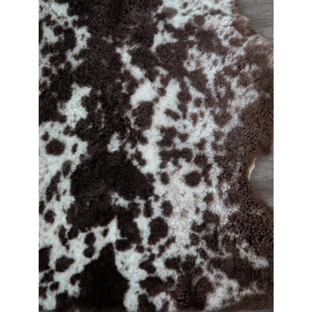 A plush tibet highland spotted sheepskin rug with natural brown and white patterns in an irregular shape