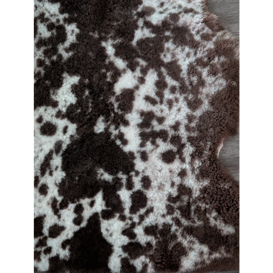 A plush tibet highland spotted sheepskin rug with natural brown and white patterns in an irregular shape