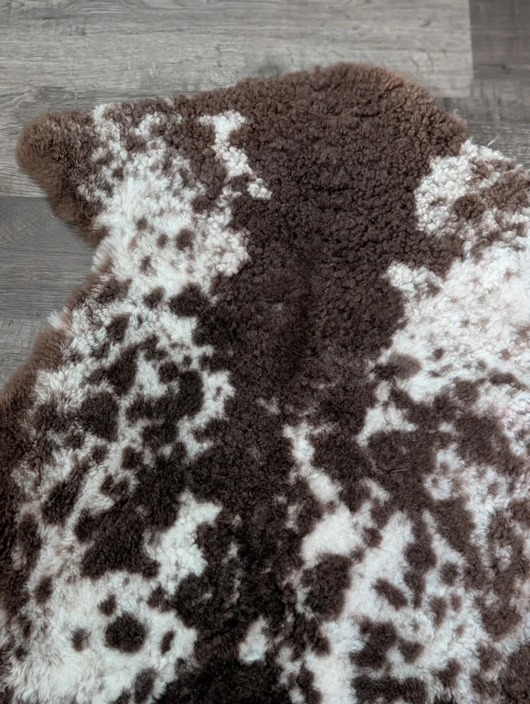 A plush tibet highland spotted sheepskin rug in brown and white with a soft fluffy texture measuring 40 by 25 inches