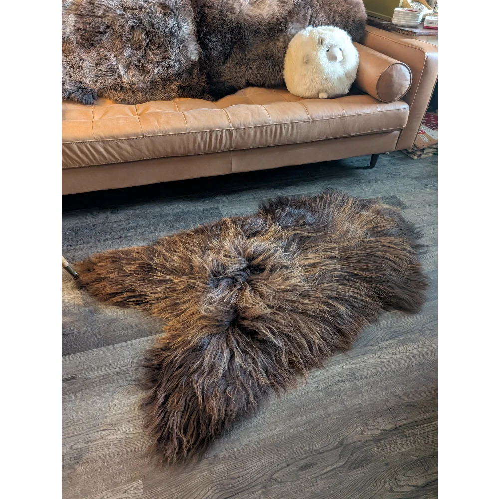 A plush long wool icelandic sheepskin rug in natural bronze with soft shaggy texture on wooden floor