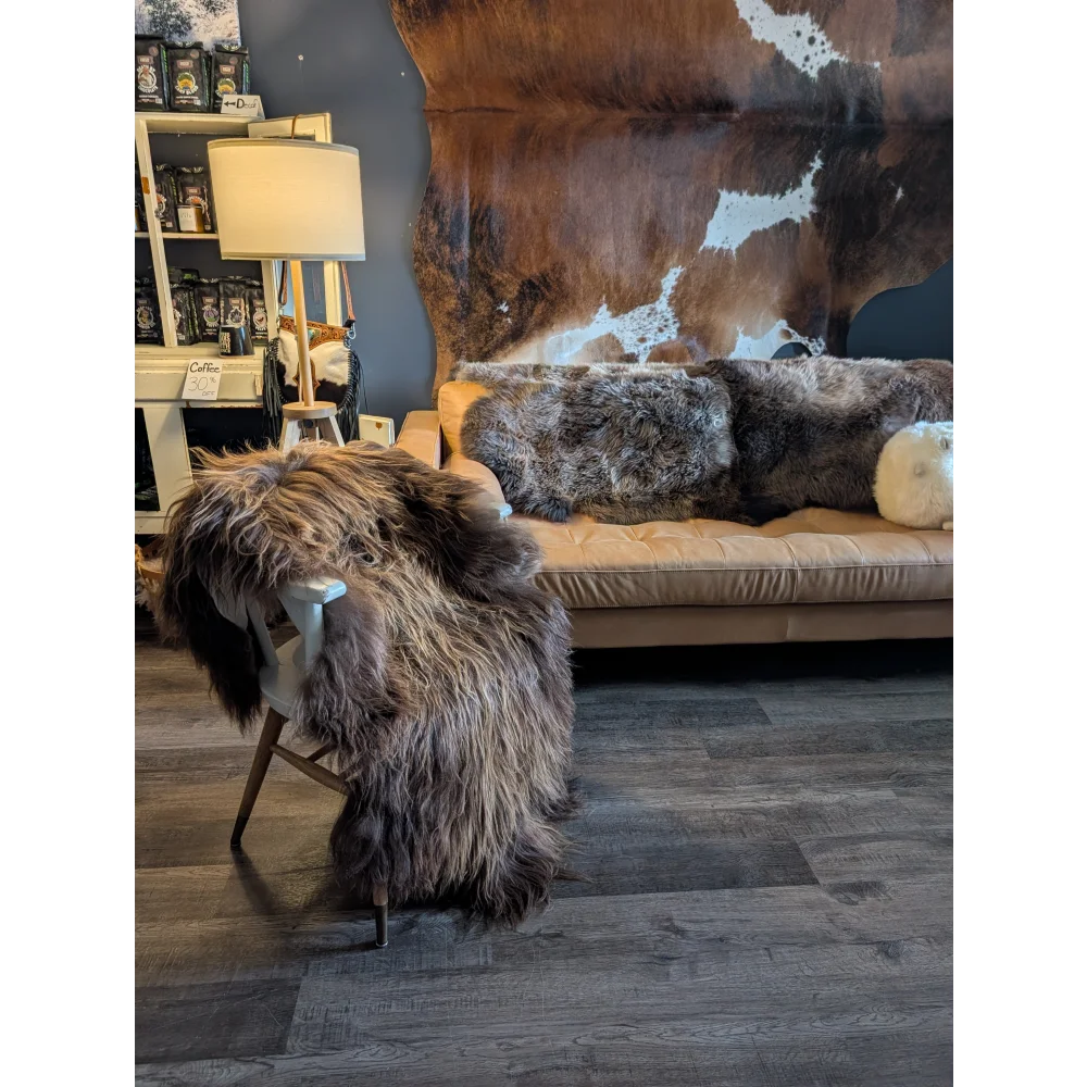 Thick shaggy brown wool icelandic sheepskin rug draped over white wooden chair with angled legs natural bronze color