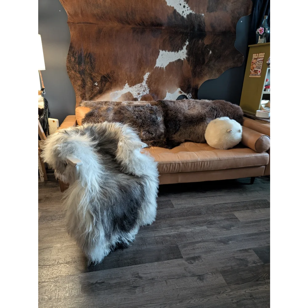 Tan leather sofa with a long wool icelandic thick fluffy brown and white sheepskin throw draped over it